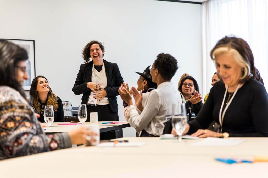 Group of women sitting at tables sharing ideas and laughing